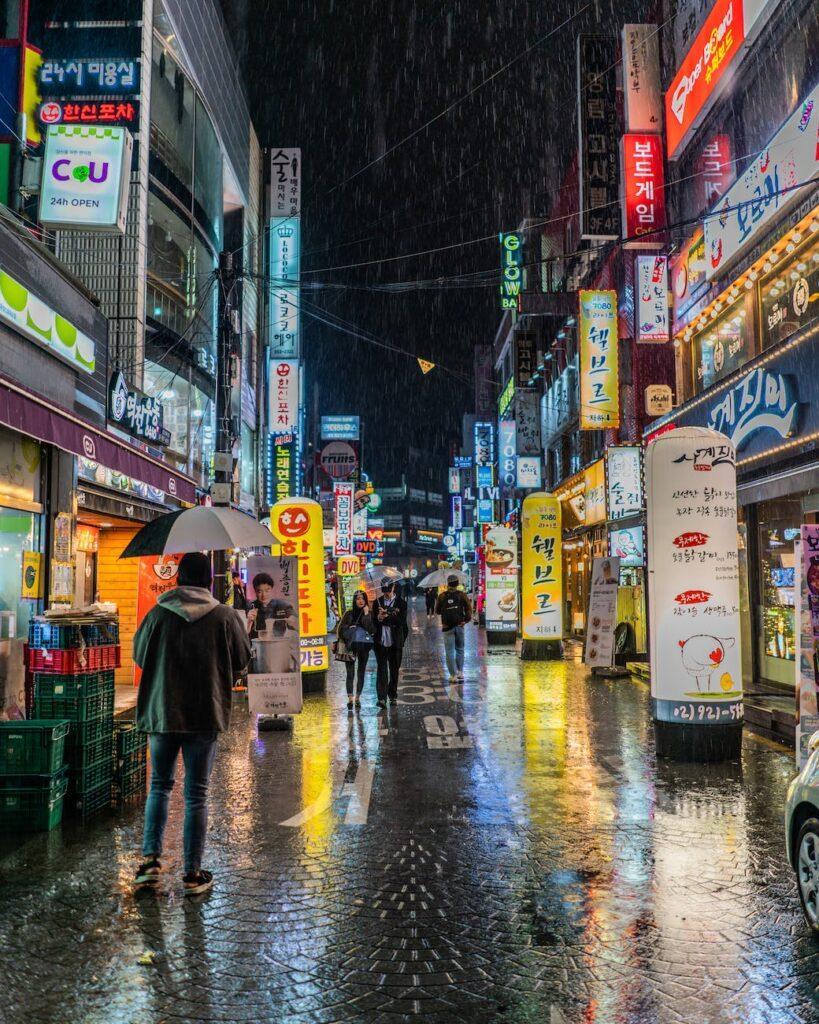 person wearing black jacket holding black umbrella walking on street